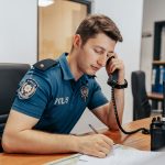 How Emotional Intelligence is Changing Law Enforcement a police officer sitting at his desk in uniform, answering a call.