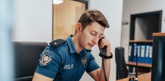 a police officer sitting at his desk in uniform, answering a call.