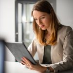 a young woman typing on her ipad.