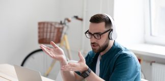 Focused,Young,Businessman,In,Eyewear,Wearing,Headphones,,Holding,Video,Call
