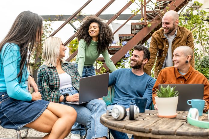 group of young diverse students sitting together in a room filled with plants.