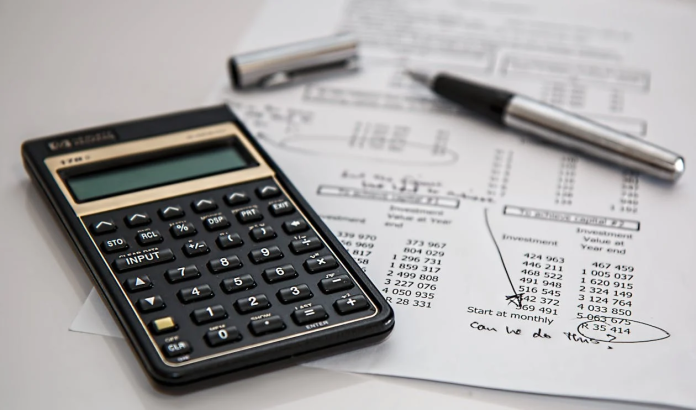 a picture of a desk with a calculator and a sheet and pen.